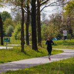 Vrouw loopt hard op een slingerend bospad in het voorjaar, een rustige omgeving voor beginnende hardlopers