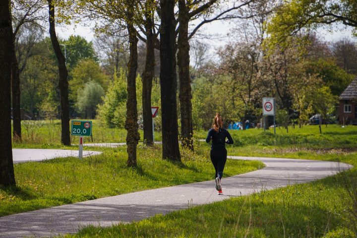 Vrouw loopt hard op een slingerend bospad in het voorjaar, een rustige omgeving voor beginnende hardlopers